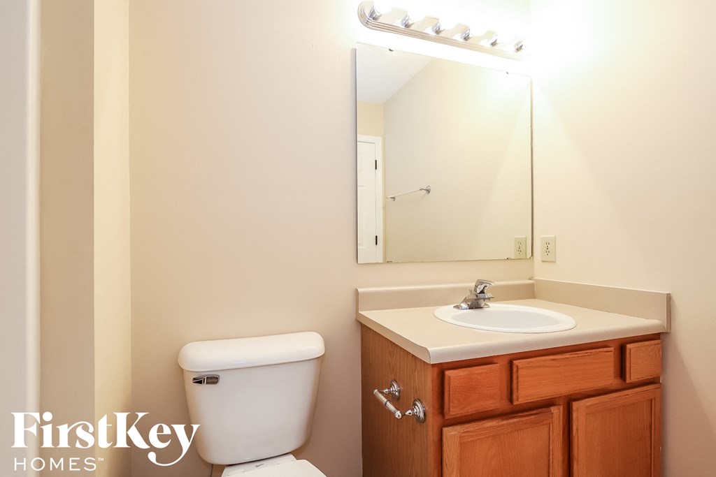 A bathroom with a toilet, sink, and mirror.