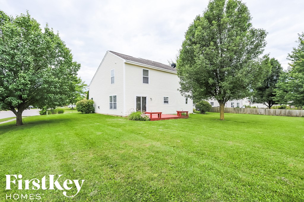 A white house with a red bench in the front yard.
