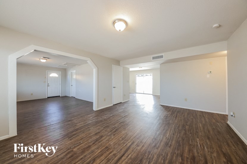 the living room and dining room of an empty house with wood flooring