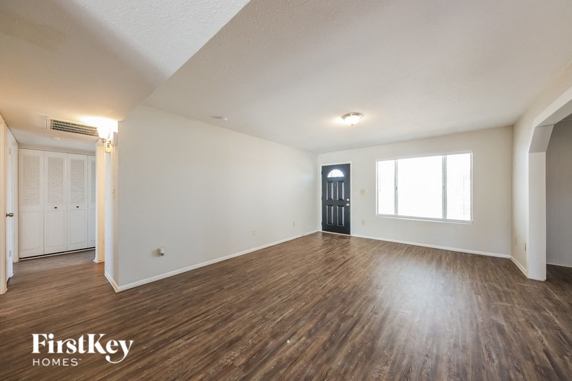 the living room and entryway of an empty house with wood flooring