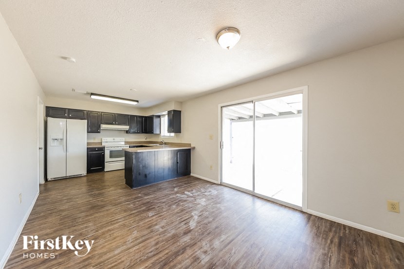 an empty living room and kitchen with wood flooring and a sliding glass door