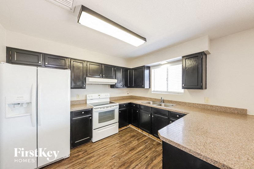 a kitchen with black cabinets and white appliances