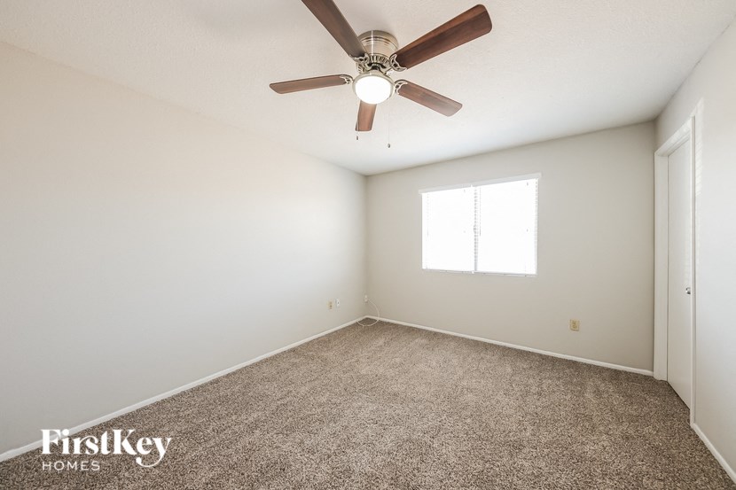 an empty room with a ceiling fan and a window