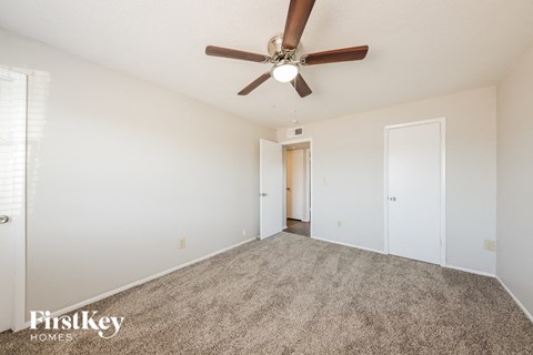a spacious living room with carpet and a ceiling fan
