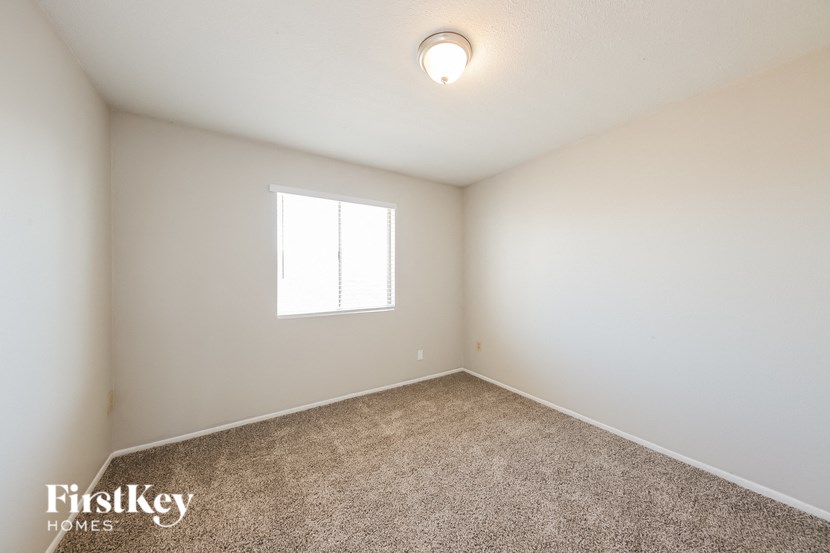 a bedroom with white walls and carpet and a window