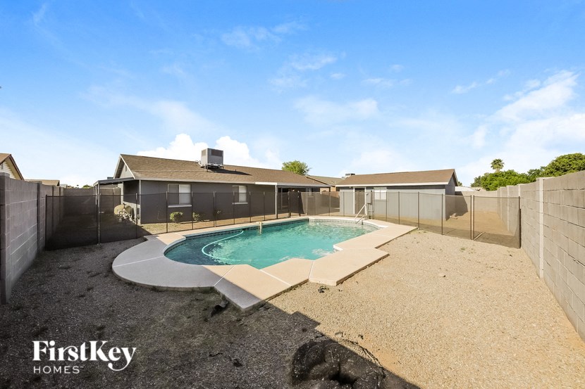 a backyard with a pool and a fence and a house