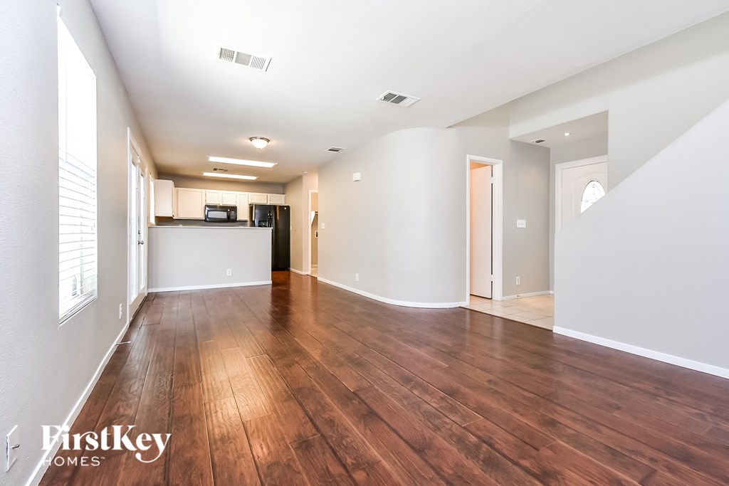 A spacious room with wooden floors and white walls.