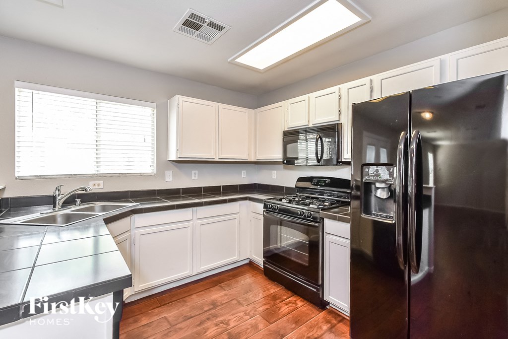 A kitchen with a black refrigerator and white cabinets.