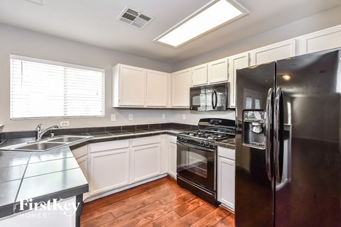 A kitchen with a black refrigerator and white cabinets.