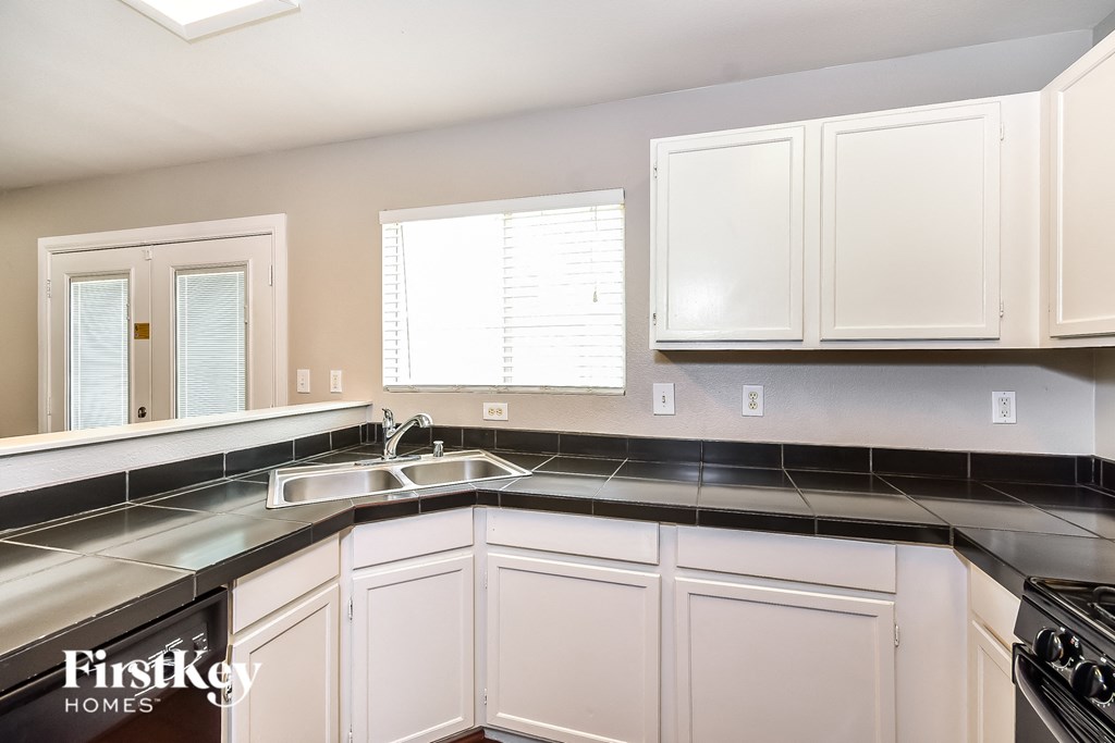 A kitchen with white cabinets and a black countertop.