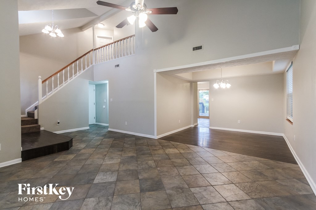 an empty living room with a staircase and a ceiling fan