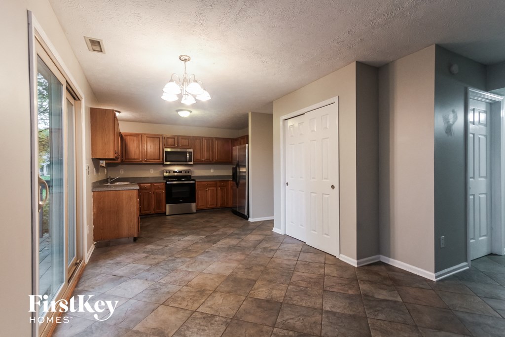 a kitchen with wooden cabinets and tile floors and a white door