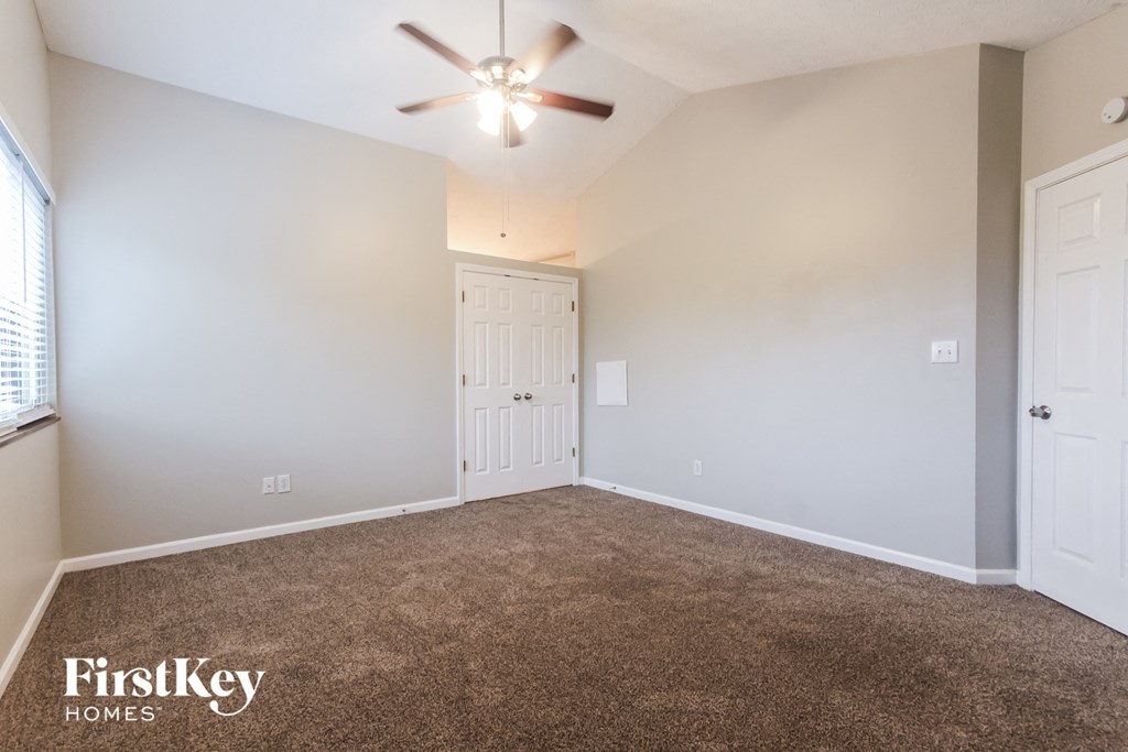 the spacious living room with carpet and a ceiling fan