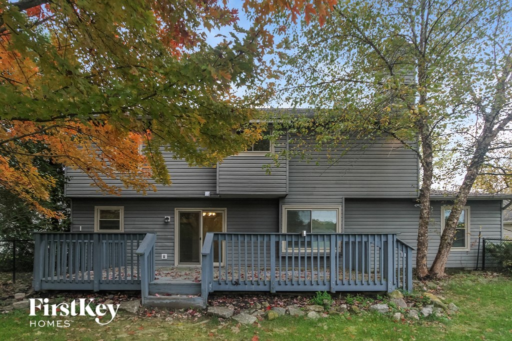 a deck in front of a gray house with a blue fence