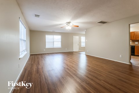 A spacious room with wooden floors and a ceiling fan.