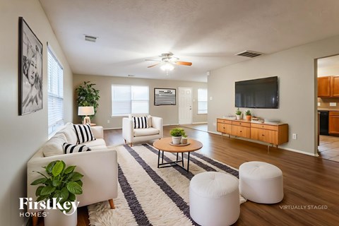 A living room with a white couch, a coffee table, and a television.