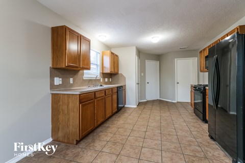 A kitchen with wooden cabinets and a black refrigerator.