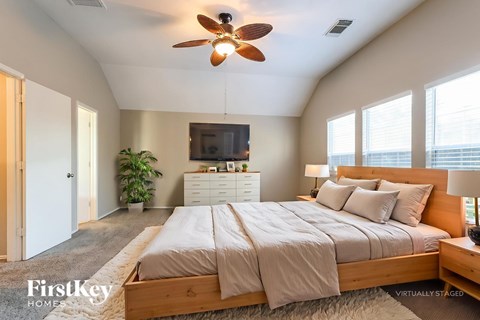 A bedroom with a large bed and a ceiling fan.