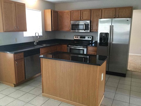 A kitchen with wooden cabinets and a black countertop.