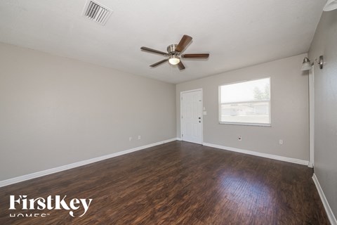 A room with a ceiling fan and wooden flooring.