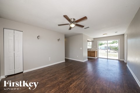 A spacious room with a ceiling fan and wooden flooring.