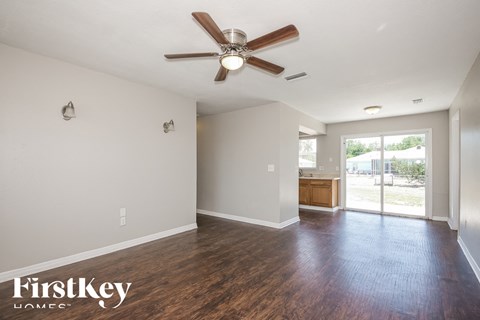 A room with a ceiling fan and wooden flooring.