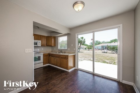 A kitchen with wooden cabinets and a view of a parking lot through the sliding glass doors.