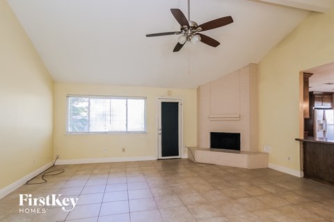 A spacious room with a fireplace and a ceiling fan.