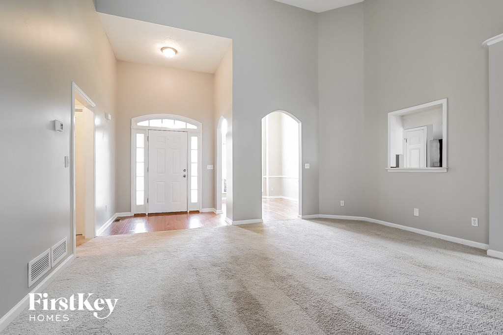 A spacious, empty room with a carpeted floor and a large window.