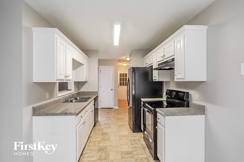 A kitchen with a black refrigerator and white cabinets.