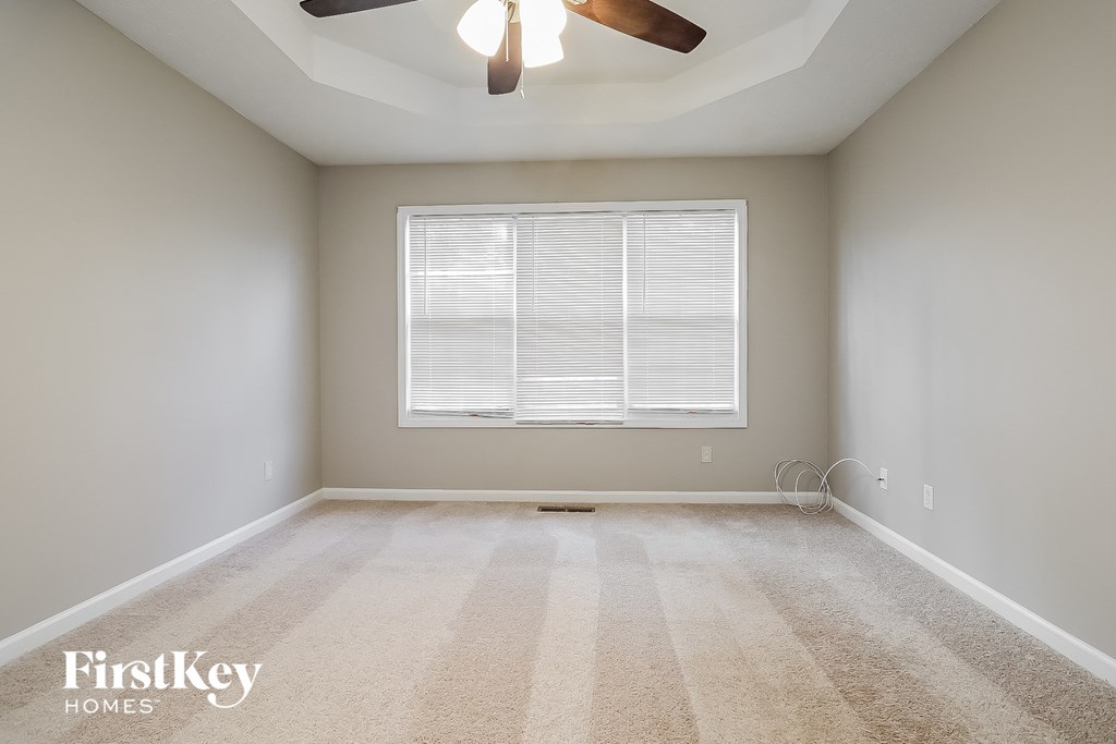 A room with a carpeted floor and a ceiling fan.