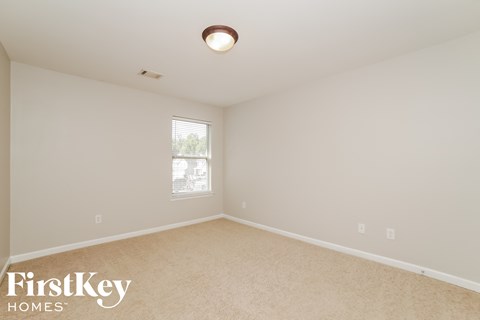 a bedroom with beige carpet and a window