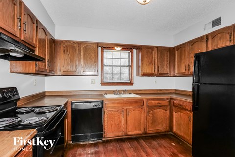 A kitchen with wooden cabinets and a black refrigerator.