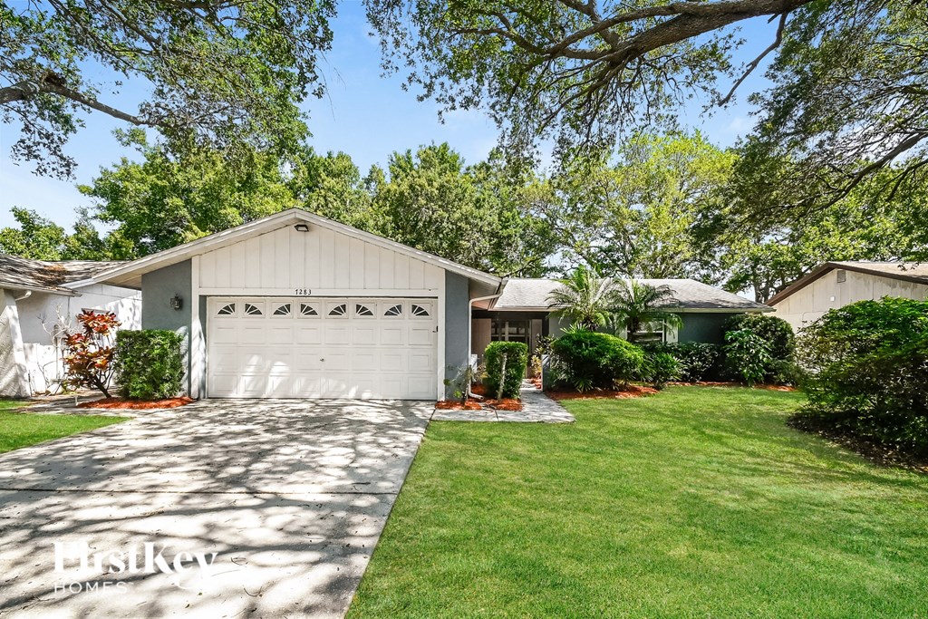 a white garage with a white house and a lawn