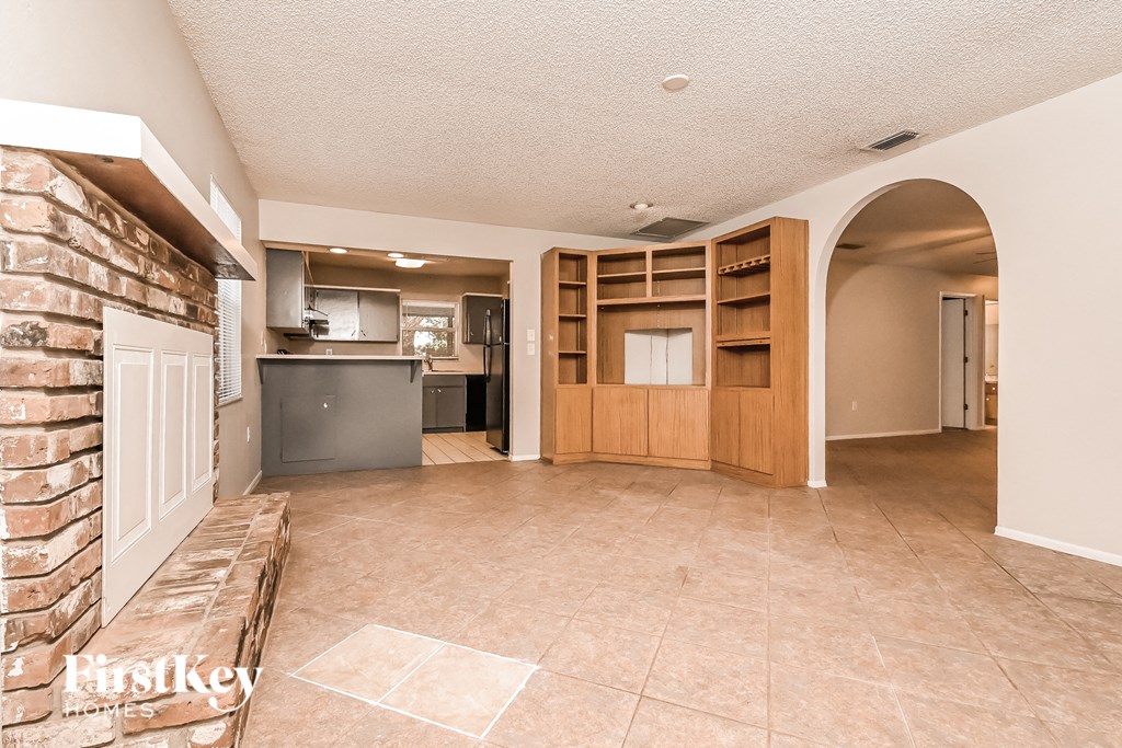 a kitchen and living room with a brick wall and wooden shelves