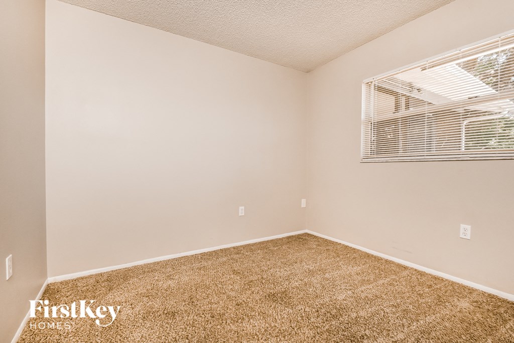 the spacious bedroom has carpet and a window