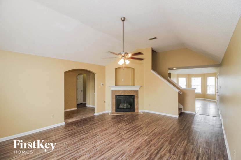an empty living room with a fireplace and a ceiling fan
