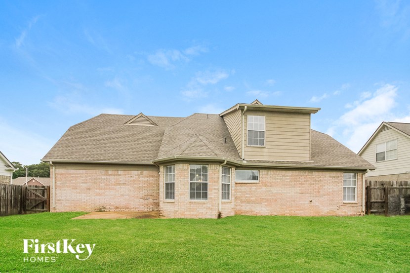 side view of a brick house with brown roof and green grass