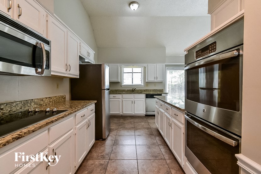 A kitchen with a refrigerator, oven, and microwave.