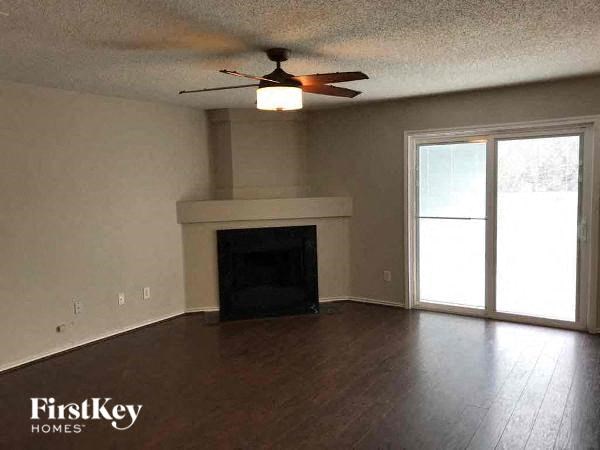 A living room with a fireplace and a ceiling fan.