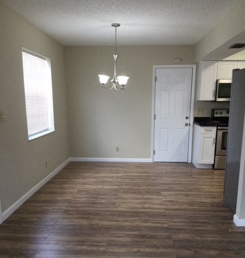 an empty living room with a kitchen and a white door