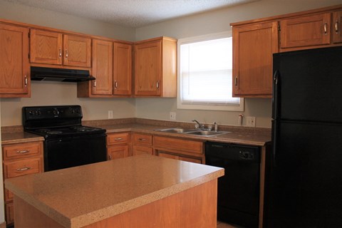 A kitchen with black appliances and wooden cabinets.