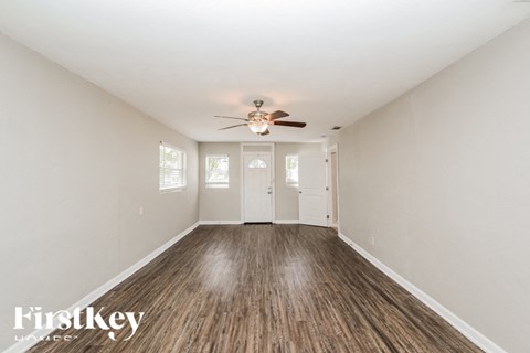 A spacious room with wooden floors and a ceiling fan.