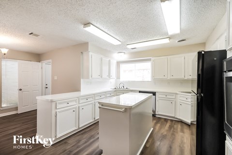 A kitchen with white cabinets and a black refrigerator.
