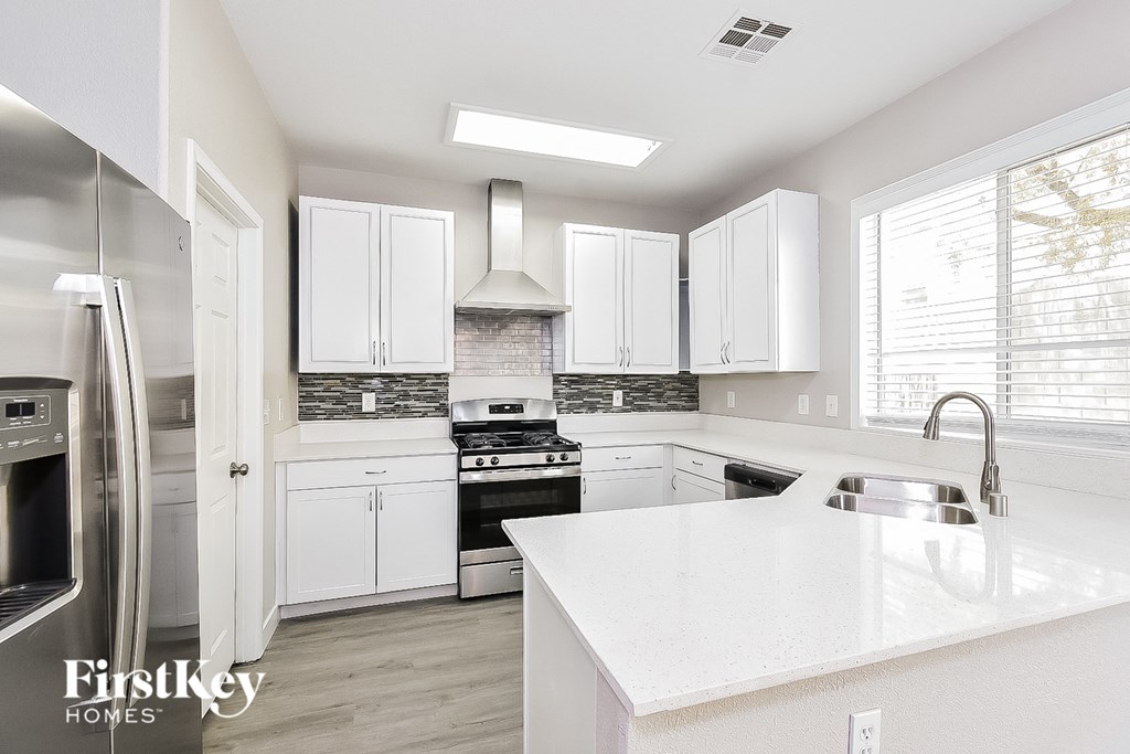 a white kitchen with stainless steel appliances and white counter tops