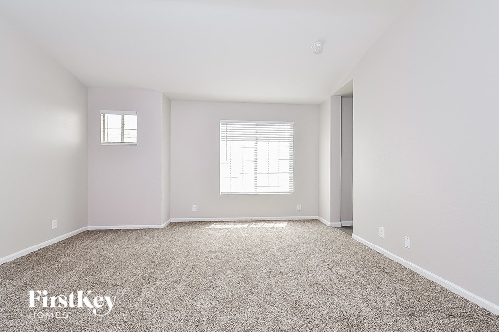a spacious living room with carpet and a window