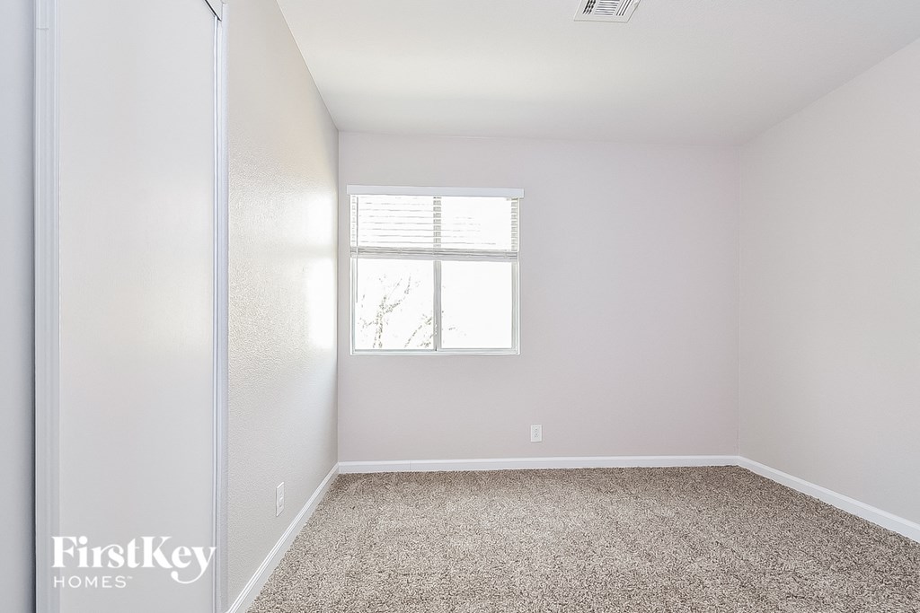 a bedroom with white walls and carpet and a window