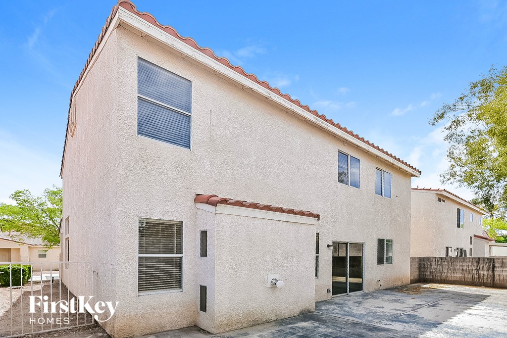 the exterior of a white brick building with a driveway and trees