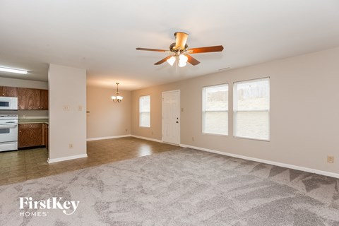 A spacious living room with a ceiling fan and a rug on the floor.