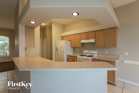 A kitchen with a white counter top and wooden cabinets.